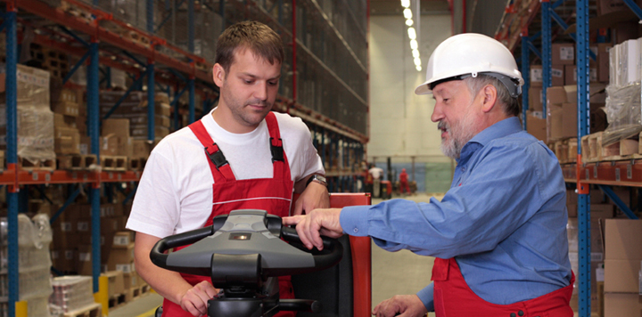 two warehouse workers learning how to use machinery